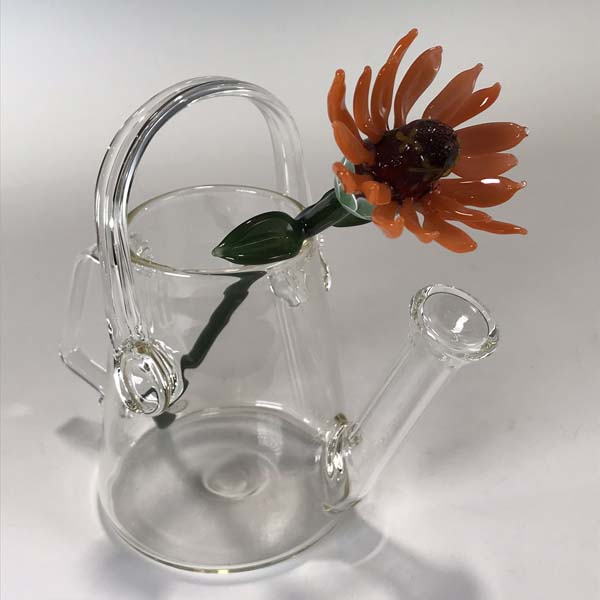 A glass flower sits in a transparent glass flower pot.